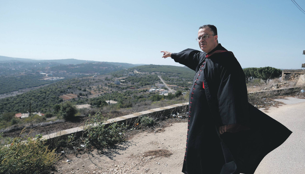 L’archevêque maronite de Tyr, Monseigneur Abdallah, montre la frontière avec Israël, située au sommet de la colline visible au loin. / ©Gaby Leygues