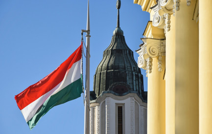 Le drapeau national hongrois à côté de l&#039;église dans la ville de Debrecen / ©iStock/majorosl
